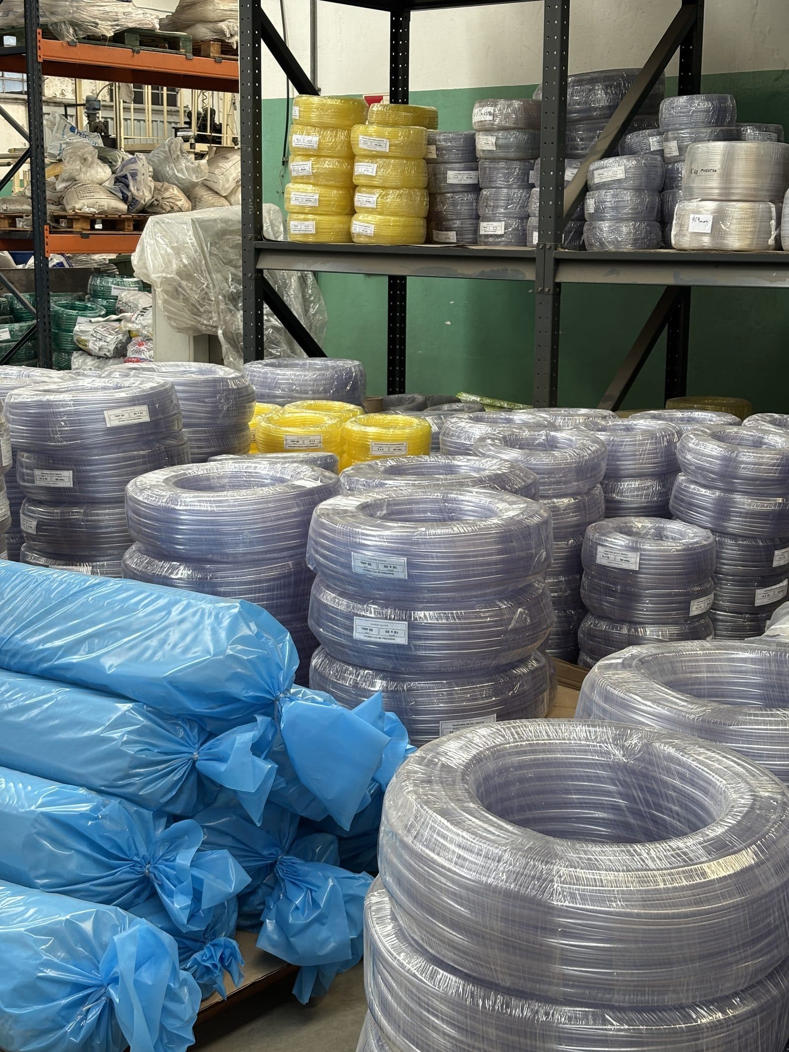 Depósito de planta con rollos de manguera de PVC apilados en estanterías