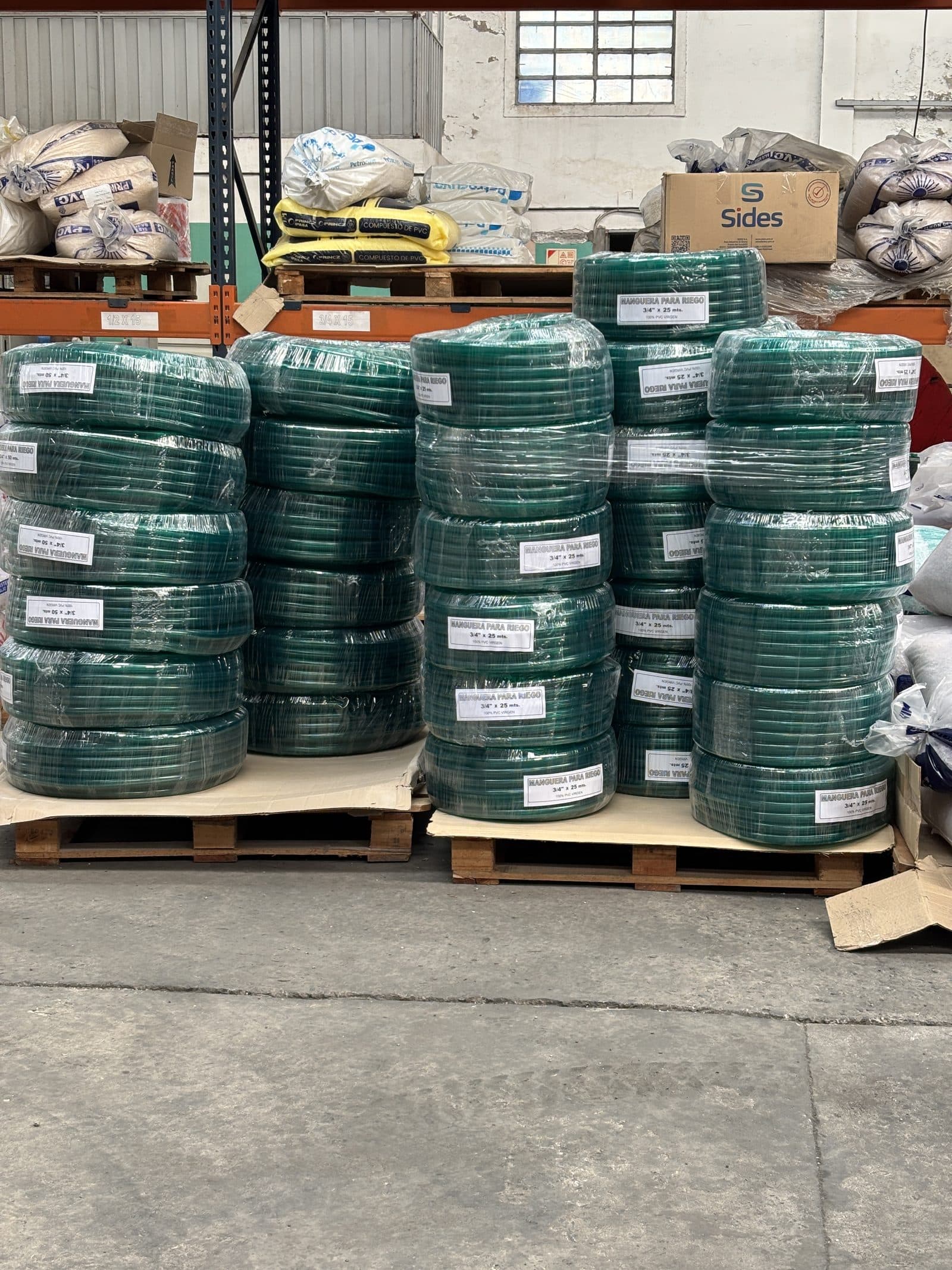 Rollos de manguera para riego apilados en depósito, listos para despacho